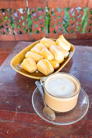 Fresh coffee and jackfruit cooked on a wood table.の写真素材