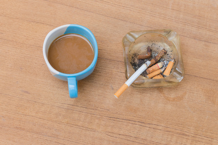 Coffee and burning cigarette in ashtray,soft-focus wooden table background.の写真素材