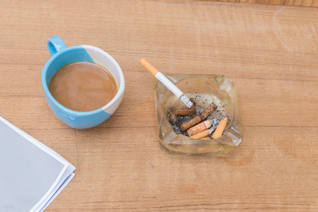 Coffee and burning cigarette in ashtray,soft-focus wooden table background.の写真素材