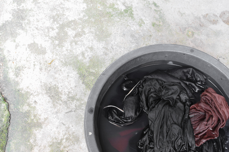 Soak dirty clothes in the basin black for clean,Thailand washing clothes style ancient and soaking with detergent. (select focus clothes and soft-focus background)の写真素材