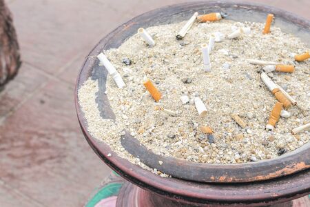 Cigarettes butt in sand ashtray.( select focus front Cigarettes and Blur blurred a background)の写真素材