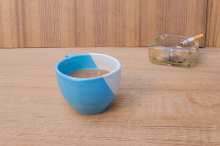 Coffee and burning cigarette in ashtray,soft-focus wooden table background.の写真素材