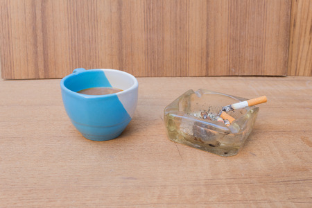 Coffee and burning cigarette in ashtray,soft-focus wooden table background.の写真素材