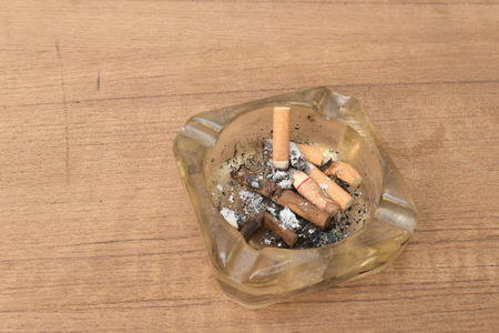 cigarette with an ashtray on the wood table, Many filter cigarette a small ashtray, no smoking concept.(soft-focus  wood table)の写真素材