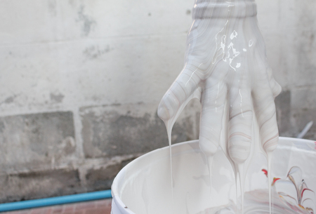 Close up Painter mixing white, Color dripping down, hand with colors mix, painted home in the work  : ancient form paint mixing : Select focus with shallow depth of field and soft-focus background.の写真素材