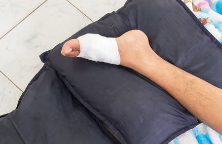 Gauze bandage the foot,treating patients with foot ulcers,male is wrapping his Foot injury with bandage.( select focus front  toe)の写真素材
