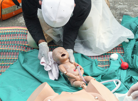 Doctor, paramedic,  The refresher training to assist childbirth newborn with medical baby dummy in...