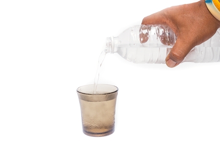 Male hand holding a bottle of Drinking water Pouring  ,into a Glass of very cold water, Drinking water thirsty.(select focus front Glass)の写真素材