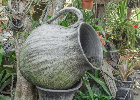 Old big earthen jar for water which has thallophytic plant cling, big water jar shaped like a glass in the gardenの写真素材