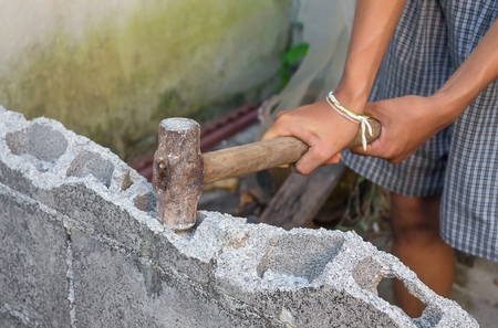 hammer in hand breaking brick wal  : young power use  Hammer smash a brick wall In construction : select focus Hammer, Blur blurred background.の写真素材