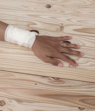 Gauze bandage the  hand contusion. treating patients with hand with a wrist left, male With gauze is wrapping his injury On a wooden table .( select focus front Gauze bandage wrist and soft background)の写真素材