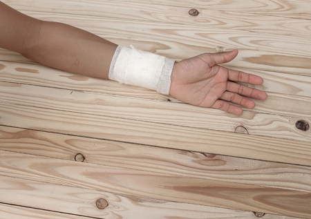 Gauze bandage the  hand contusion. treating patients with hand with a wrist left, male With gauze is wrapping his injury On a wooden table .( select focus front Gauze bandage wrist and soft background)の写真素材