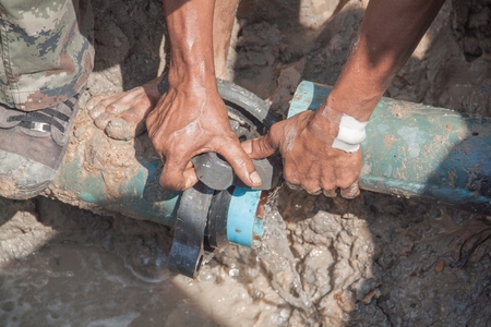 worker male repair plumbing broken  pipe in the hole with water flowの写真素材