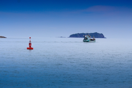 Floating red marine buoy and boat on blue sea, gulf of Thailand  with copy space.の写真素材