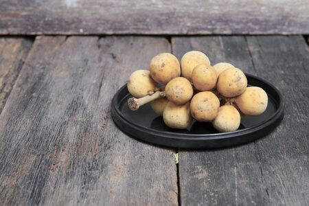 southern langsat, Wollongong on a black plate in wooden background tropical fruit  at South of Thailandの写真素材