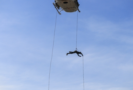 Soldier rappelling from helicopter in blue skyの写真素材