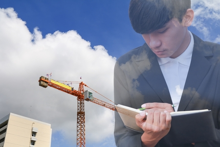 businessman  with notepad in hand signing documents   in construction  site workplace, double exposure concept.の写真素材