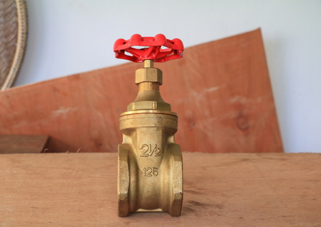 brass valve with red knob in a factory plumber
 on wooden floor backgroundの写真素材