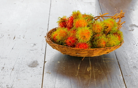 rambutans fruit in basket on a wood desk background.の写真素材