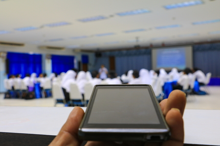 smartphone hand holding  in seminar conference classroom: Select focus with shallow depth of field.の写真素材