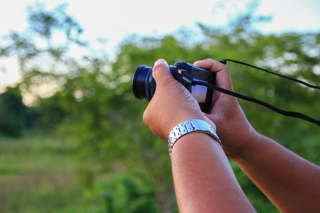 hand holding camera photograph in nature backgroundの写真素材