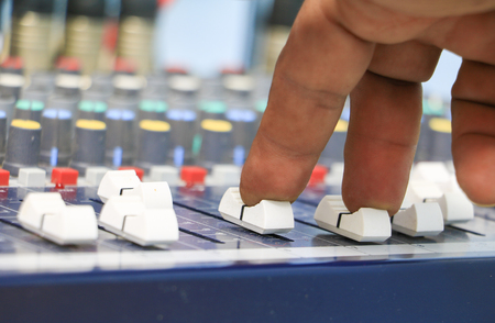 hand on a sound mixer control equipment old which has dust. select focus with shallow depth of field.の写真素材