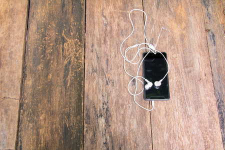 white earphone on mobile phone with table old wooden vintage background and copy space. top viewの写真素材
