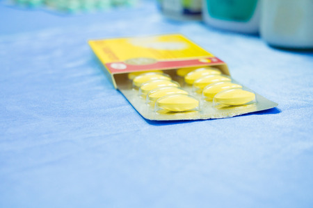 drug yellow or treatment medication in packages plastic pill. on  blue fabric table  select focus with shallow depth of field with copy space add textの写真素材