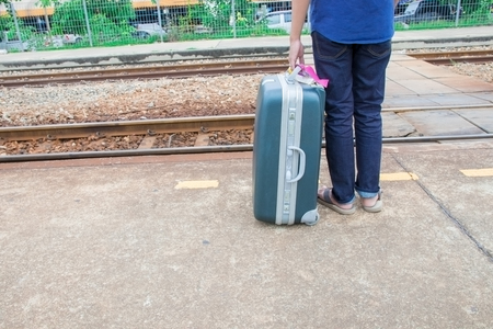 leg male of travel put jeans stand and suitcase wait train in station  trail platform with copy spaceの写真素材