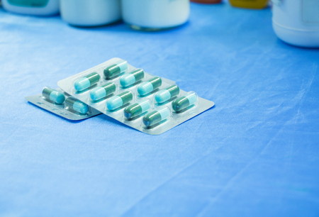 drug capsule green - azure or treatment medication in packages plastic pill. on  blue fabric table  select focus with shallow depth of field with copy space add textの写真素材