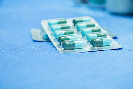 drug capsule green - azure or treatment medication in packages plastic pill. on  blue fabric table  select focus with shallow depth of field with copy space add textの写真素材
