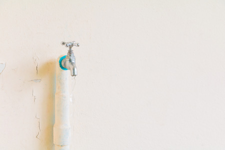 faucet color silver - bronze with water drop and old pipe in wall cement background with copy space add textの写真素材