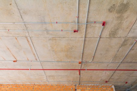 Metal pipes in Construction and fire sprinkler on red pipe are hanging from ceiling interiorの写真素材