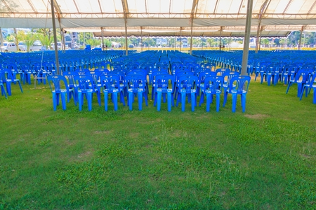Row of blue chairs plastic on lawn in tentの写真素材