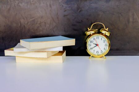 alarm clock old vintage gold and book over white on black background. with copy space add textの写真素材