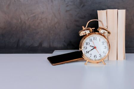 alarm clock old vintage gold and mobile phone, book over white on black background. with copy space...