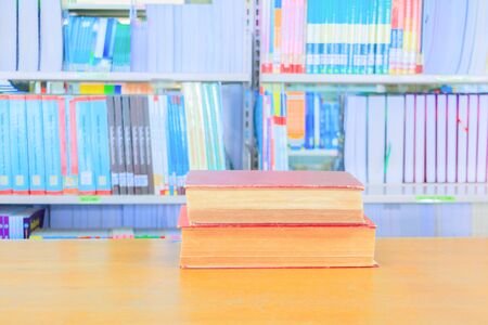 old book red and green heap in interior library school on wooden table and blurry bookshelves...