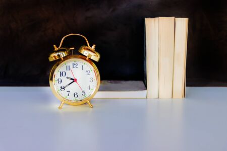 alarm clock old vintage gold and book over white on black background. with copy space add textの写真素材