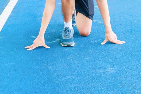 arm male touch floor start pose training running on track rubber blue in public park with copy space...