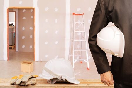 engineering businessman holding helmet white in the work gypsum board wall interior decoration of home in construction siteの写真素材