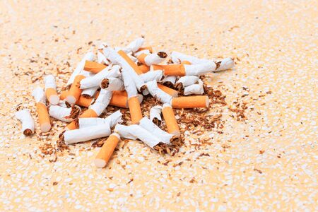 Pile cigarettes broken on table terrazzo flooring yellow background. health care concept stop quitting smoking.の写真素材