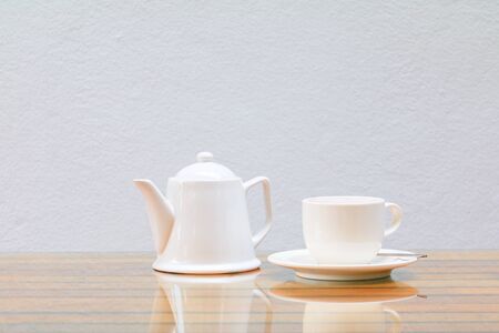 coffee cup and teapot white On the glass table wooden and a cement wall background. copy spaceの写真素材