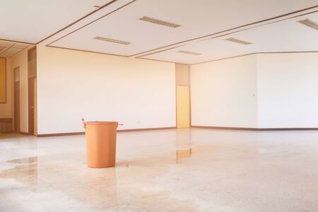 water leak drop interior office building in red bucket from Ceiling and flow on terrazzo floorの写真素材