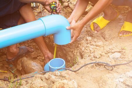 broken pipe in hole with water motion at roadside and plumber working repair