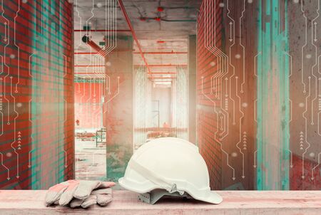 white safety helmet and glove on wood table and Double exposure digital circuit line technology interior construction site backgroundの写真素材