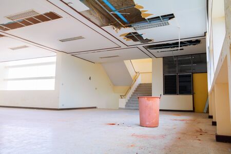 repair leak water pipe in under gypsum ceiling interior office building and bucket waterの写真素材