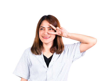 woman smiling uplift left hand showing v-sign fingers doing victory sign number two symbol with fingers on face isolated on white backgroundの写真素材