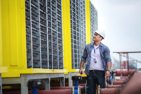 Engineer inspects the large air conditioner with a happy smile.の写真素材