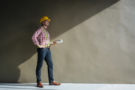 Portrait of an architect builder studying layout plan of the rooms, serious civil engineer working with documents on construction site.の写真素材