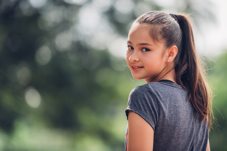 Portrait of a beautiful girl  in the bokeh of leaves is a green backdrop of nature, The girl smiled happily at the camera.の写真素材